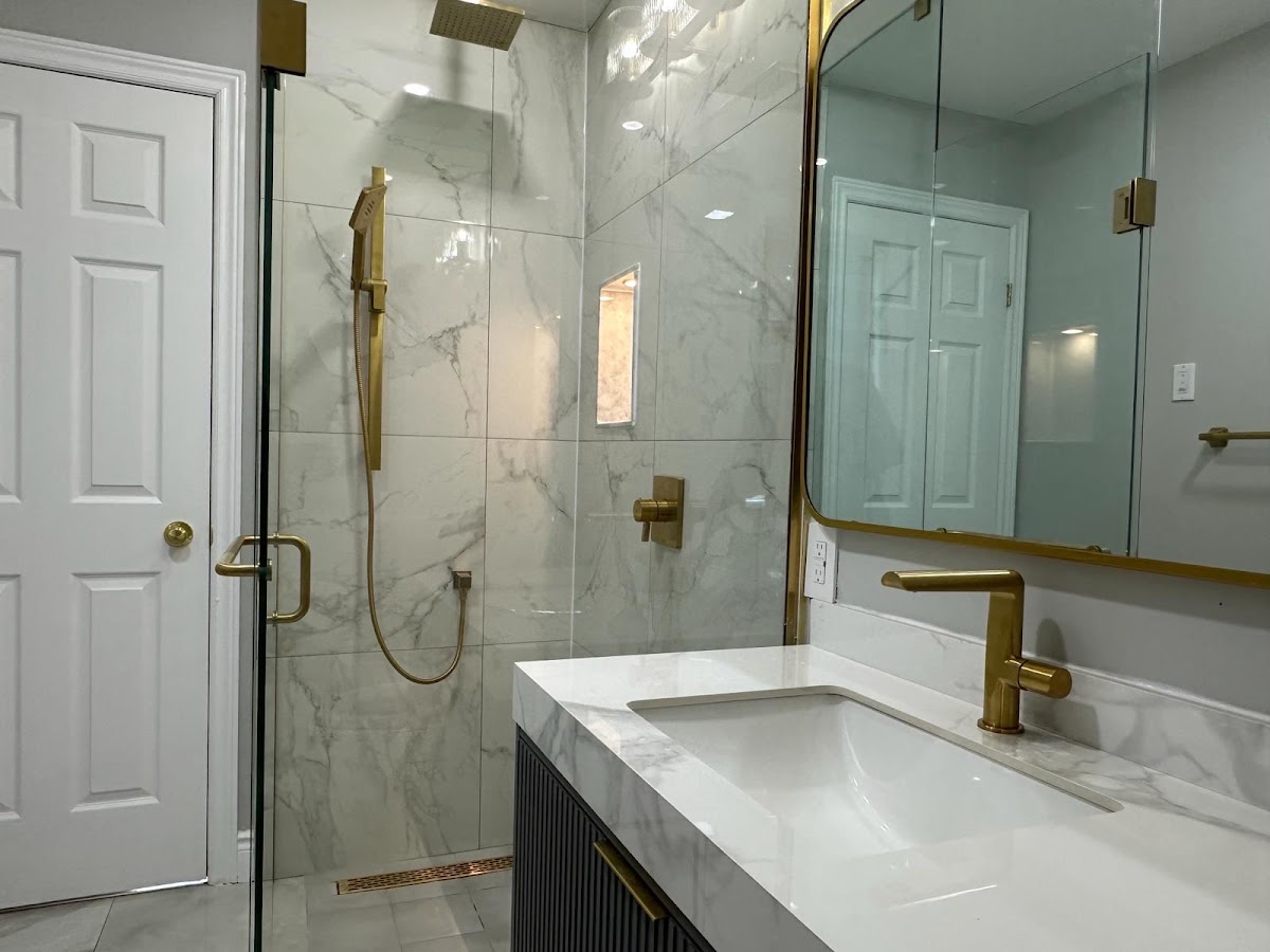Finished bathroom with curbless walk-in shower, marble-look tile, brushed gold rainfall fixture, and linear drain